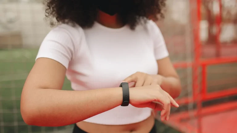 Une femme consulte son bracelet connecté à l'extérieur