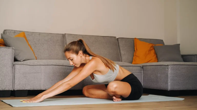 Une femme étire le dos sur un tapis dans son salon
