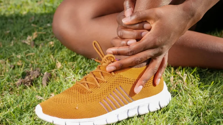 Une main masse la cheville d'un coureur, chaussure de running aux pieds