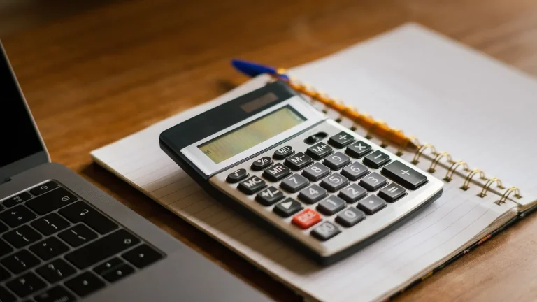 Un cahier de comptes et une calculatrice sur un bureau pour établir son budget