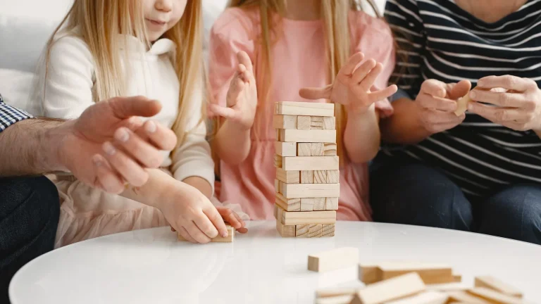 Une famille joue autour d'une table basse à un jeu de société en bois